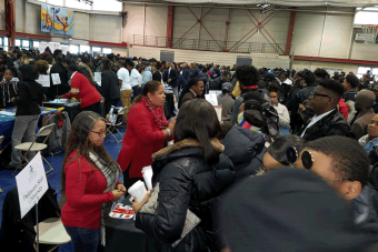 View of a historic red brick university building surrounded by lush trees and walking paths.